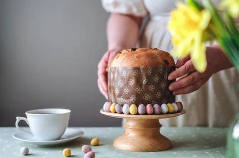 Woman holding Easter cake on table setting for Easter celebration in room Stock Photos