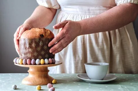 Woman holding Easter cake on table setting for Easter celebration in room Stock Photos
