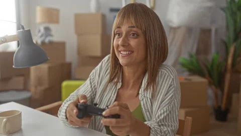 Woman holding game controller in unpacked living room building, smiling and.. Stock Footage 339145563