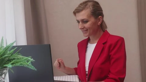 Woman holding gift box while video chatting with her friend via laptop at home Stock Footage 249060951