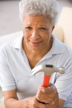 Woman holding hammer looking unsure Stock Photos