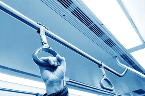 Woman holding onto a handle on a train Photos