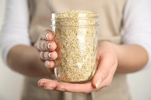 Woman holding jar with white quinoa on light background, closeup Stock Photos