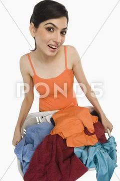 Woman holding laundry basket filled with clothing Stock Photos