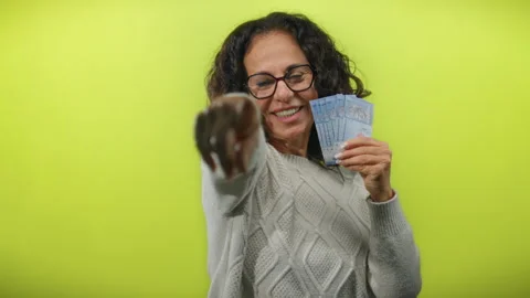 Woman holding malaysian ringgit, making peace gesture against a yellow back.. Stock Footage 314280517