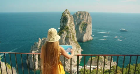 Woman holding map above dramatic Faraglioni sea cliffs at coastal viewpoint in Stock-Footage 342464629