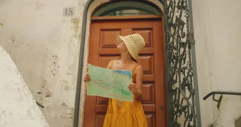 Woman holding a map in front of a rustic door in Italy during summer vacations Stock Footage 307360475