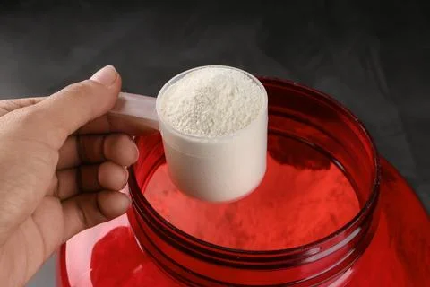 Close Up of Women with Measuring Scoop of Whey Protein, Jar and