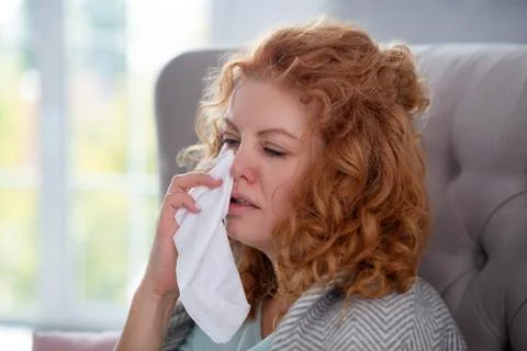 Woman holding napkin while sneezing and feeling dizzy Stock Photos