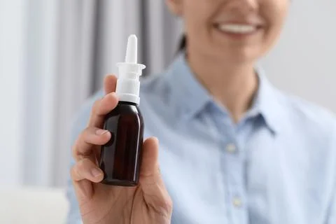 Woman holding nasal spray bottle indoors, closeup. Space for text Stock Photos