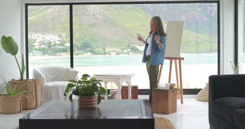 Woman holding object stepping to table lifting canvas preparing art area at Stock Footage 335269046