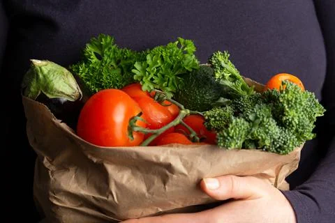 Woman holding paper carrier bags, full of fresh raw vegetables. Healthy food. Stock Photos