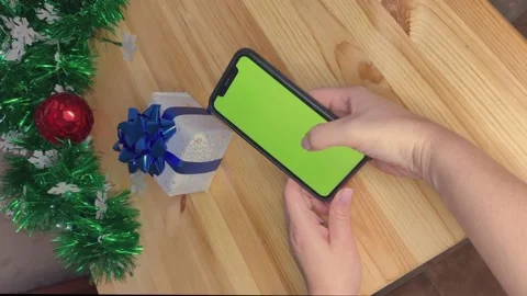 Woman holding phone with green screen on table with new year decorations Stock Footage 164545341