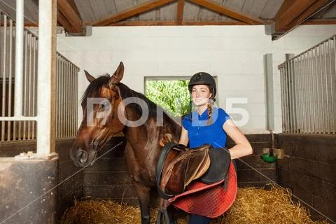 Woman holding saddle while preparing her horse Stock Photos