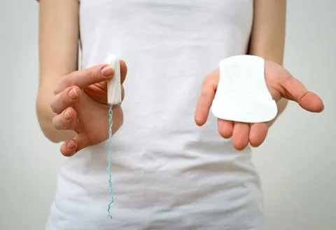 Woman holding sanitary napkin and tampon in her hands. Stock Photos