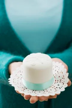 Woman holding a small white cake on a doily Stock Photos