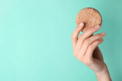 Woman holding solid shampoo bar against turquoise background, closeup. Space  写真素材
