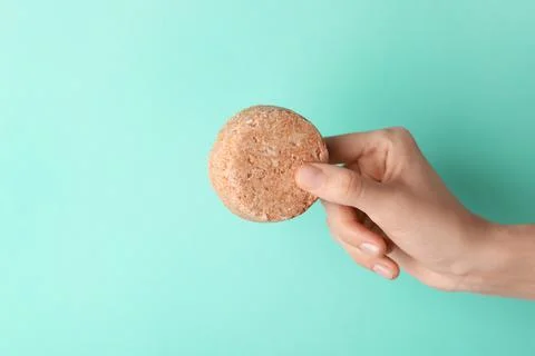 Woman holding solid shampoo bar against turquoise background, closeup. Space  写真素材