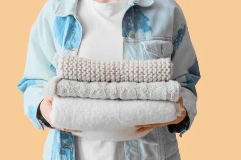 Woman holding stack of clean folded warm knitted sweaters and clothes for lau Foto stock