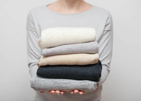Woman holding stack of sweaters Foto stock