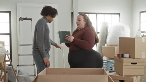 Woman holding tablet gestures while packing moving boxes and preparing ship.. Stock Footage 337390335