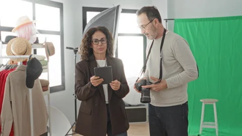 Woman holding tablet while man operates dslr camera beside green screen and.. Stock Footage 337416773