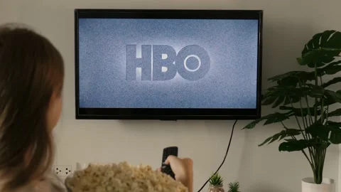 Woman holding a TV remote and watch HBO show on screen Stock Footage 210679114