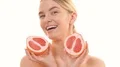 The woman holding two halves of a grapefruit on the white background 4k or 4k+ Resolution