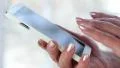 Woman holding a white cell phone. Woman looking the photos in her smartphone HD Footage