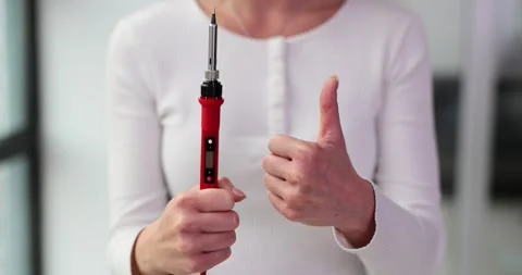 Woman holds battery testing device showing thumb up Stock Footage 257609746