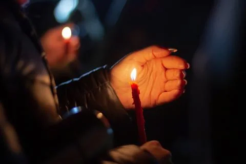 A woman holds a candle in her hand, covering the flame from the wind with her Stock Photos