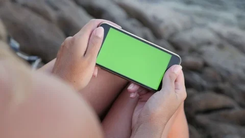 Woman holds green screen gadget by the sea slow-mo Stock Footage
