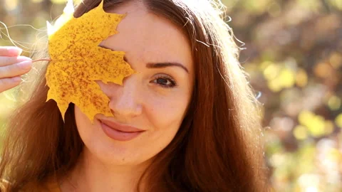 Woman holds in hands maple leaf in the autumn sunny day in the forest with Stock Footage 97635201