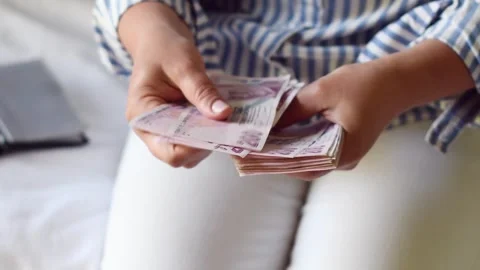 Woman holds large stack of 200 Turkish lira bills in front of her, spreads it Stock Footage 285676014