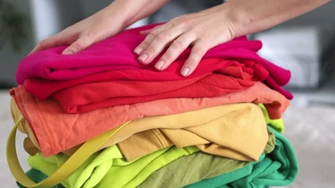 A woman holds a stack of brightly colored clothes in her hands. Stock Footage 236964070