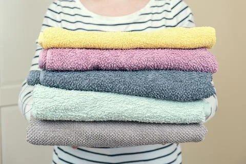 Woman holds a stack of clean terry towels. Folding clean linen Stock Photos