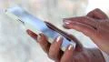 Woman holds white cell phone. Woman looks the photos in her smartphone HD Footage