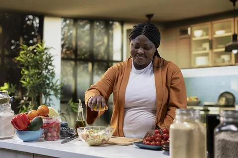 Woman home chef adding squeezed lemon juice in fresh salad bowl Stock Photos