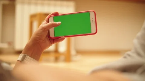 Woman at Home Lying on a Couch using Smartphone with Green Mock-up Screen, Doing Video stock 111404949