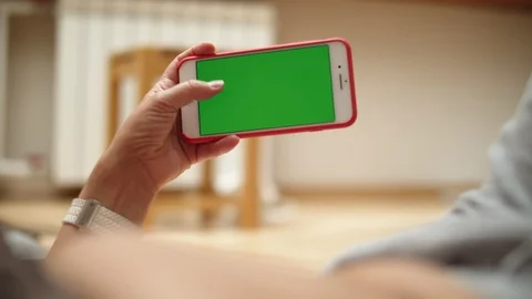 Woman at Home Lying on a Couch using Smartphone with Green Mock-up Screen, Doing Video stock 111405146
