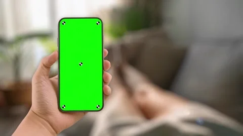 Woman at home lying on couch using smartphone with green mock up screen chroma Stock Footage 306171987