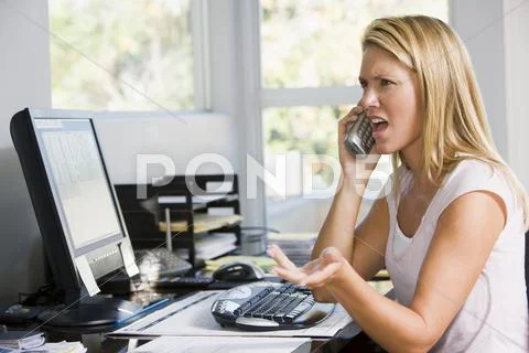 Woman in home office with computer using telephone frowning Stock Photos