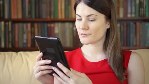 Woman at home reading e-book. Paper vs digital reading, e-books replacing Stock Footage 153604099