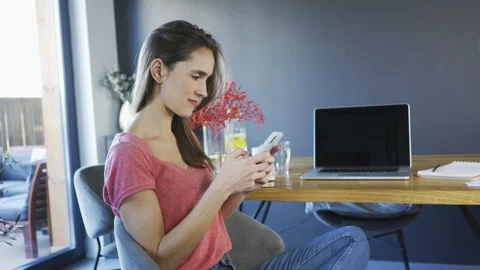 Woman at home using smartphone while sitting on chair Stock Footage 136831857