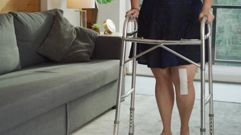 Woman at home walking with walker after knee surgery Stock Footage