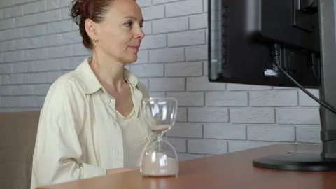 Woman with an hourglass at a computer Stock Footage 345065179