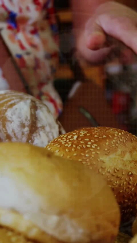 Woman hovering hand over bakery bread, hand entering frame causing flowing Stock Footage 333020558