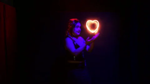 A woman in the image of a devil creates a sparkling heart in her hands Stock Footage 121405197