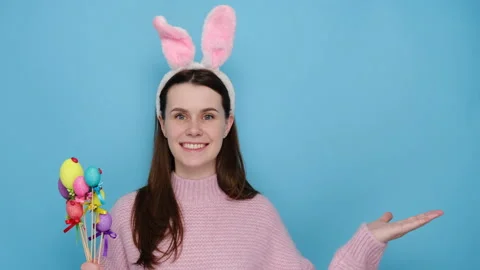 Woman in image of friendly Easter rabbit, raises palm as if showing something Stock Footage 148932322