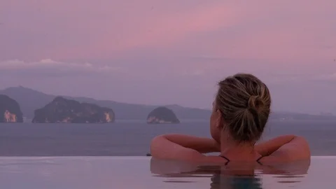 Woman in infinity pool during candy floss sunset 库存影片 90840098